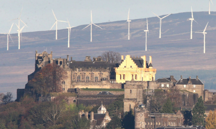 Stirling Castle with the Braes of Doune wind farm behind it in early morning sunshine.