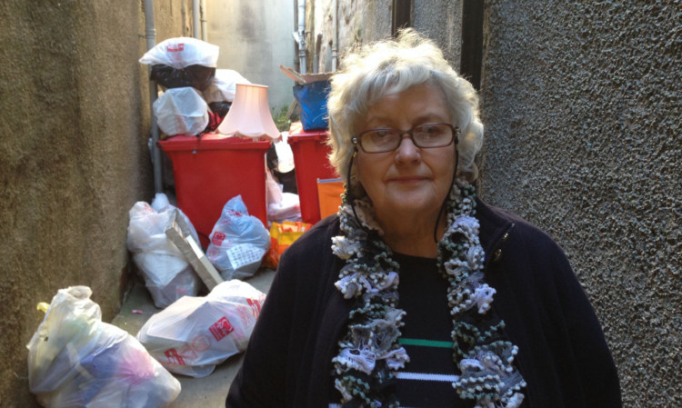 Moira Dewhurst beside rubbish dumped at the back door of the British Heart Foundation charity shop in Perths High Street.