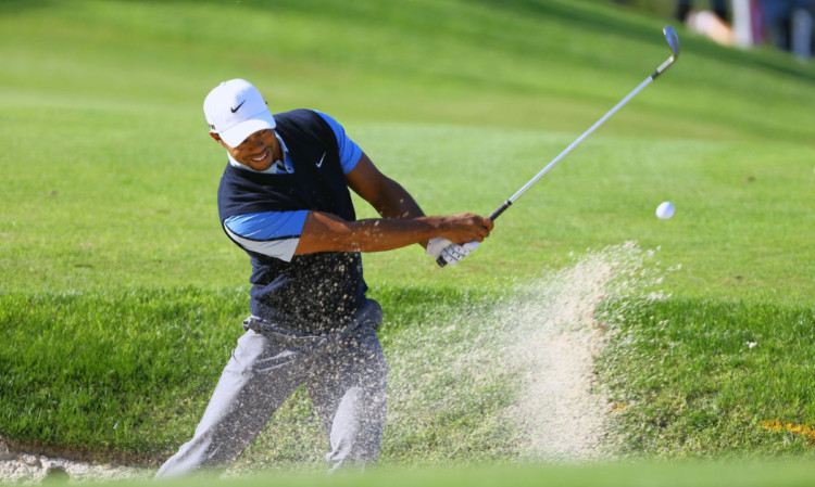 Tiger Wood plays a shot from a bunker near the 13th green.