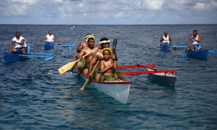 The Queens Baton is taken ashore in Nauru by locals in traditional dress.