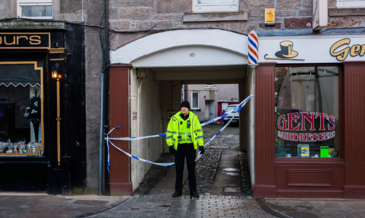 A police officer at the entrance to the block of flats on Perth High Street.