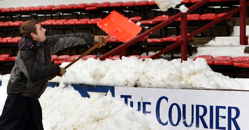 John Stevenson, Courier,10/12/10.Fife.Dunfermline,East End Park. attempts to clear the snow from the surface of the pitch to allow game to proceed tomorrow.Pic shows our advertising board disappearing as Liam Noble piles snow onto the lower terraces from the pitch.