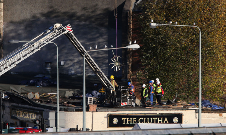 Emergency services remove the rear rotor of a police helicopter that crashed into the pub.