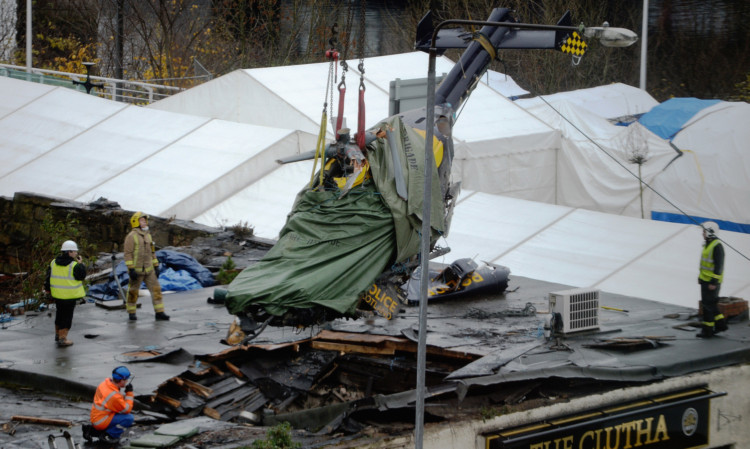 Rescuers lift the police helicopter wreckage from the roof of the The Clutha Pub.