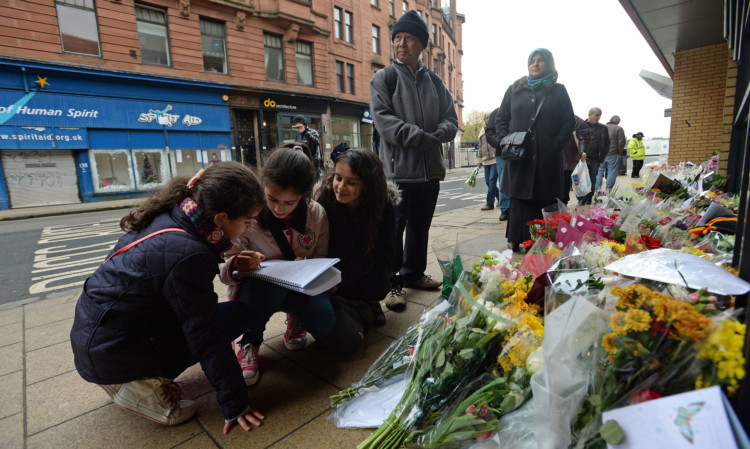 Young girls lay flowers and sign a book of condolence near to The Clutha bar in Stockwell Street.