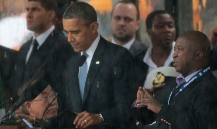 The interpreter stands alongside President Obama during his speech at the memorial service.
