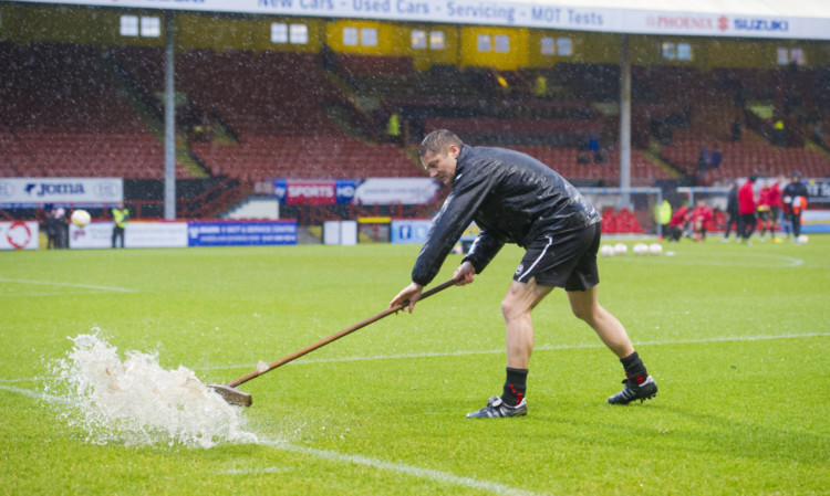 Ground staff attempt to clear the pitch of excess water.