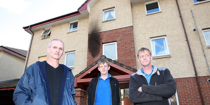 Steve MacDougall, Courier, Clay Acres Court, Dunfermline. Flat petrol bombed in the early hours of the morning. Pictured, the scorch mark and boarded up window in the background. At the front, left to right is John Stocks (intended target), Barry Moffat and Father Frank Moffat (actual victims).