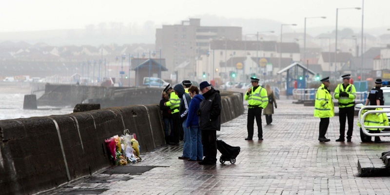Steve MacDougall, Courier, The Esplanade, Kirkcaldy. Pictures from the scene where three year old Eryk Cieraszewski died after being swept into the sea. Pictured, Police at the scene as passers by look at the floral tributes.