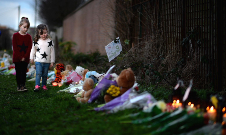 Young children look at flowers and candles laid by members of the public near to the house in Edinburgh where Mikaeel Kular was reported missing last Thursday.