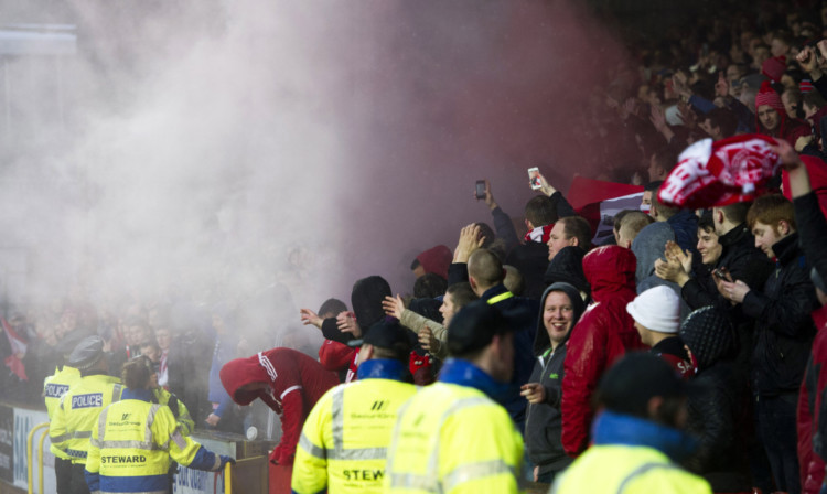 Fans enveloped in smoke as a flare is let off at Tannadice on January 1.