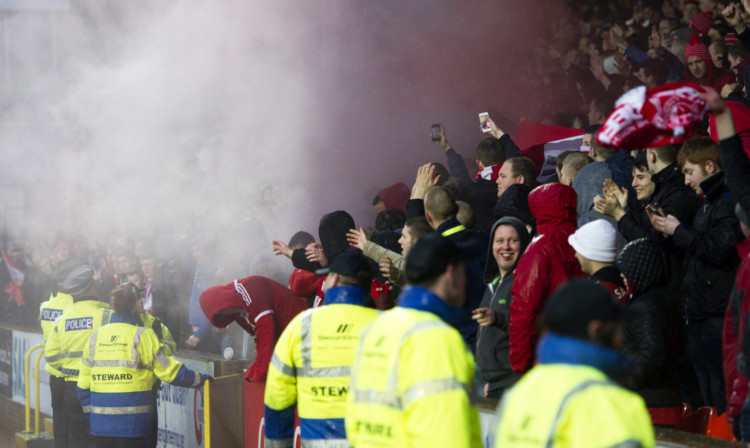 Police and stewards step in after a smoke bomb is released inside the ground on New Year's Day.