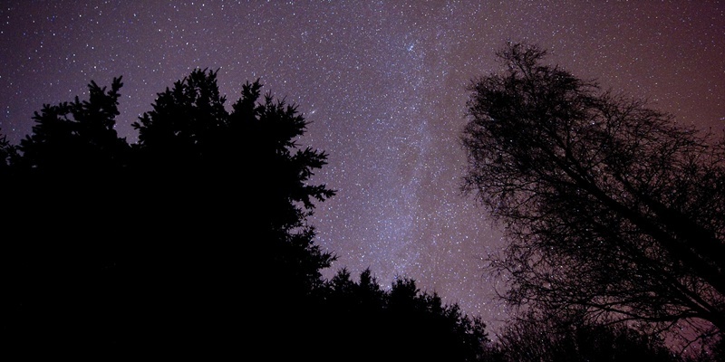 The light band of the Milky Way edge is seen in the centre of an image of the night sky over  Exmoor National Park.