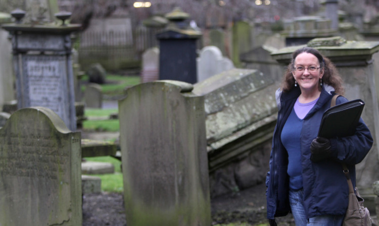 Karen in the burial ground with some of the worn, damaged and overgrown areas.