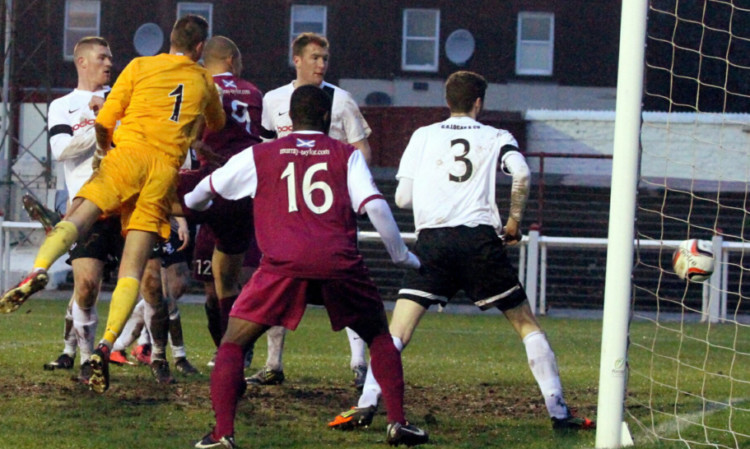 Leighton McIntosh, partly hidden by the goalkeeper, scores on his debut.