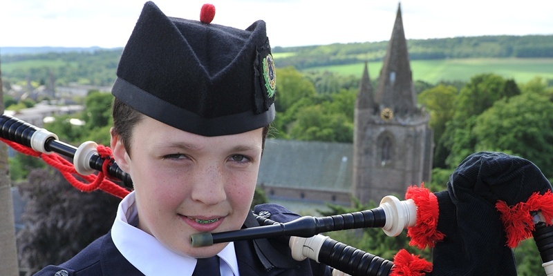 Kim Cessford - 12.06.12 - pictured at the Olympic Torch procession through Brechin - ready for his piping role on top of the Mechanics Institute is Gregor O'Neill with the cathedral in the background