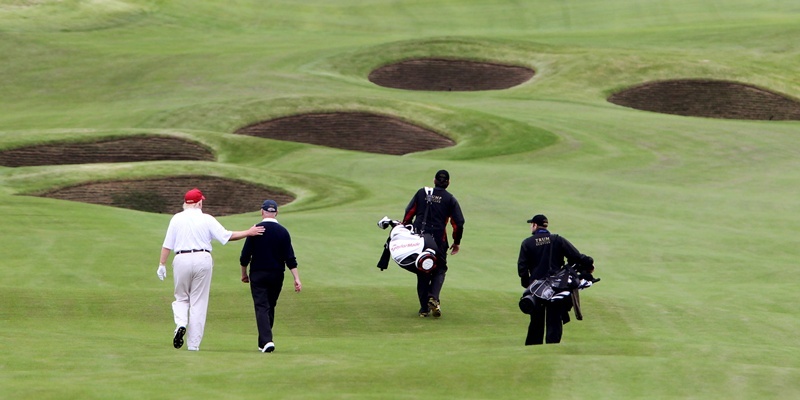 Donald Trump pats Sandy Jones, chief executive of the PGA
 on the back as they walk up the fourth fairway  of the Trump International Golf Links golf course near Aberdeen after officially opening it this morning.
