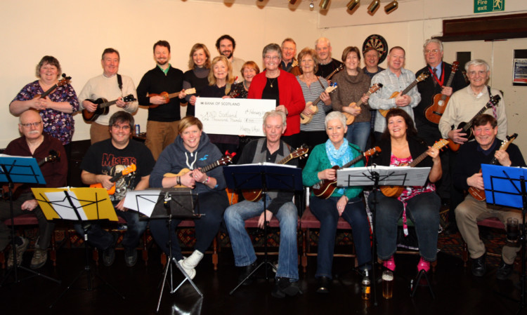 Motor Neurone Disease Scotland trustee Christina McWhirter accepts the cheque from the Happy Ukes.