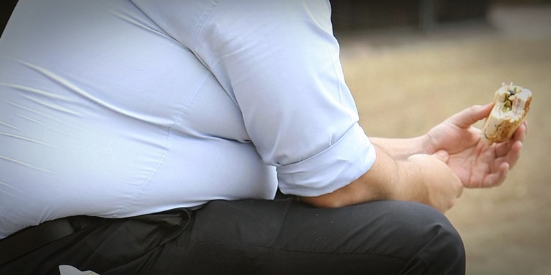 File photo dated 28/07/10 ofan overweight man eating fast food as GPs have no incentive to do more than 'tick boxes' when it comes to tackling obesity, campaigners have said.
