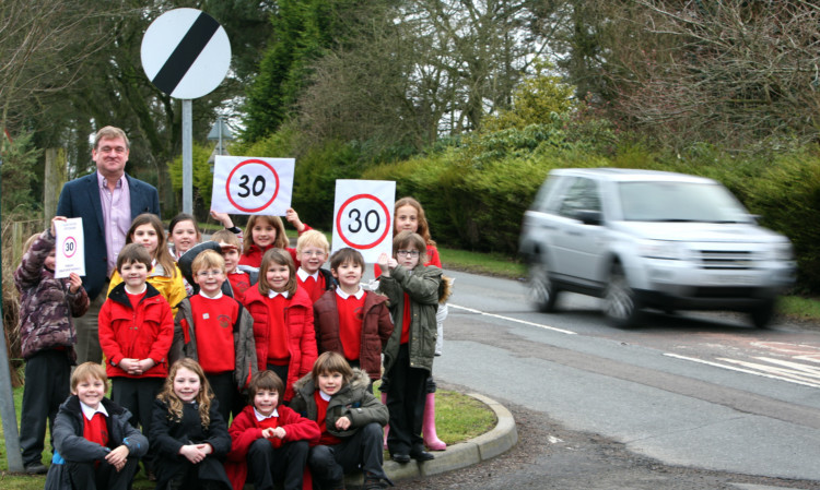 Monikie Primary School, where pupils and parents are calling for a reduced speed limit through Craigton of Monikie. Councillor Bill Bowles is shown with pupils from the school.