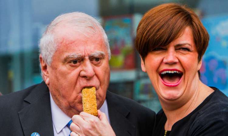 French chef Albert Roux is fed an oat bar by Julie Collier, of Iain Burnett the Highland Chocolatier.