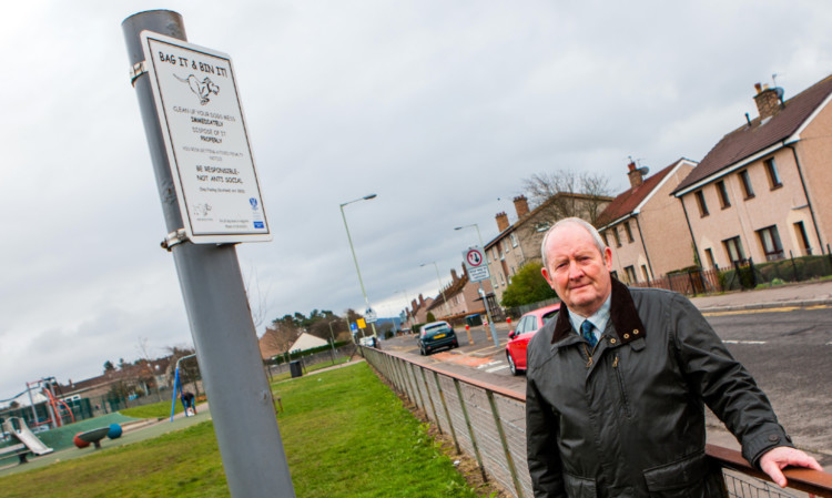 Councillor Callum Gillies alongside one of the dog fouling signs near Letham Primary School.