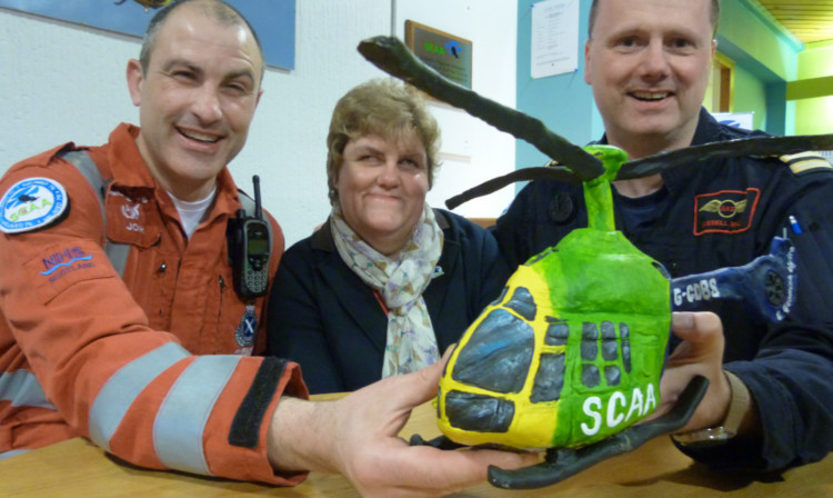 Lindsay Cant hands over her handiwork to Scotlands Charity Air Ambulance lead paramedic John Pritchard, left, and lead pilot Captain Russell Myles.