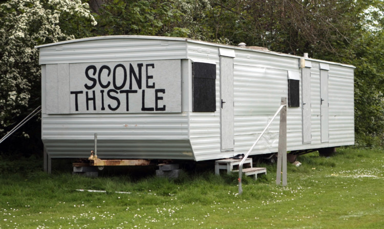 The vandalised caravan with its broken windows boarded up.