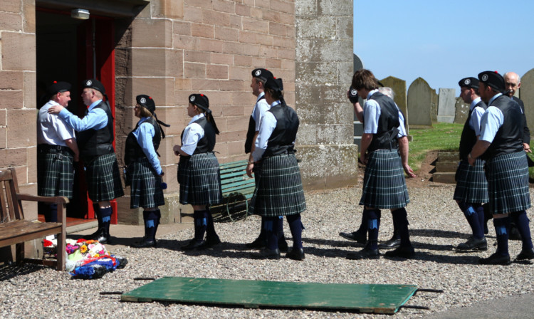 Members of the pipe band enter the church for the funeral service.