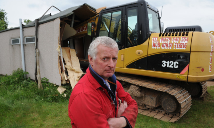 Lindsay Paterson surveys the damage after a digger was crashed into a cabin on his land.