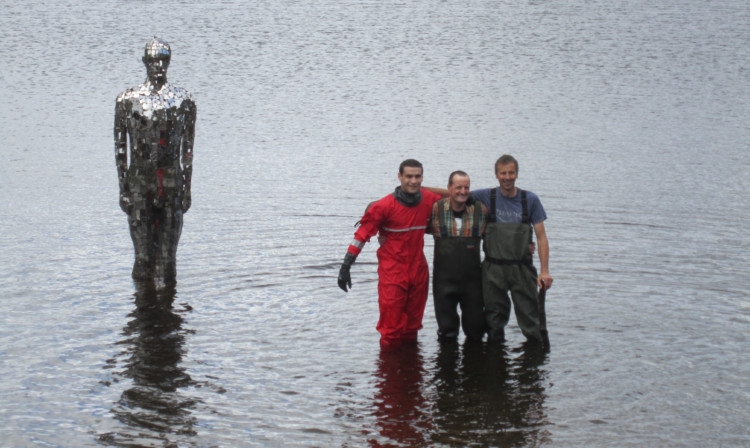 Craig Cameron, artist Rob Mulholland and Steven Alexander are dwarfed by the newly-installed statue.