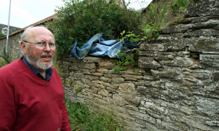 Ian Glenn beside the damaged wall in Liff last August.