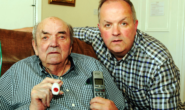 James McPherson with his son, Garth, and the dead phone and alarm pendant.