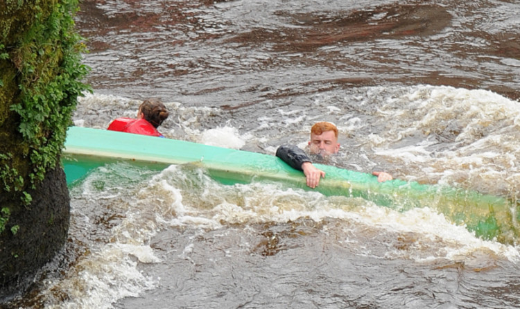 Rowers cling to a capsized boat.