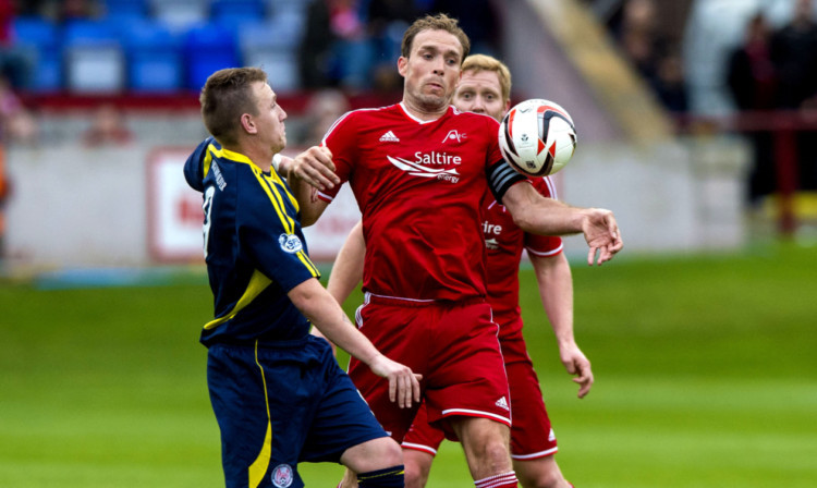 Andy Jackson battles for possession with Dons skipper Russell Anderson.