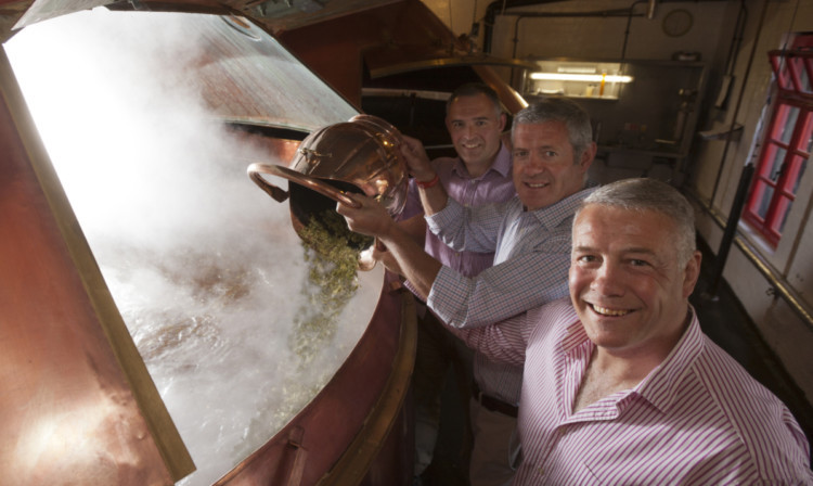 Gavin and Scott Hastings with Caledonian Brewery managing director Andy Maddock pour hops into an open-fired copper for Commonwealth Gold beer