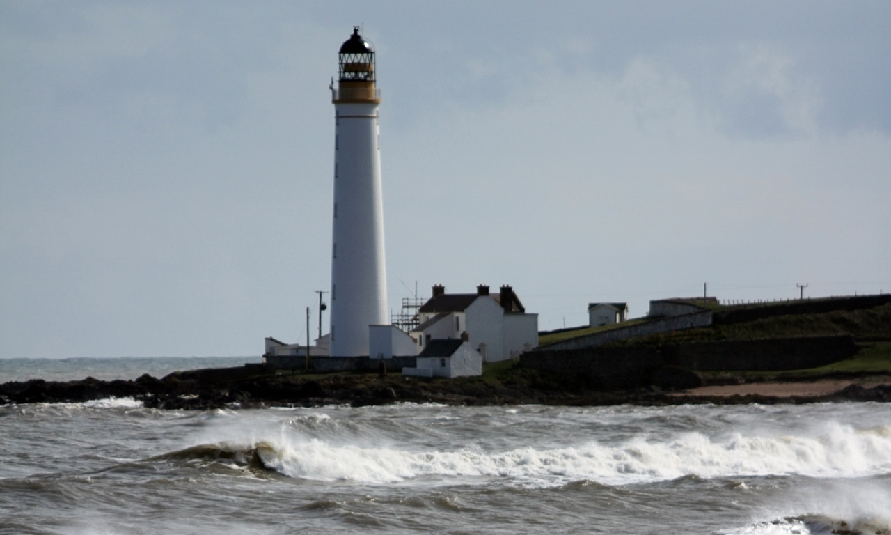 The Ferryden lighthouse with rough sea in foreground.