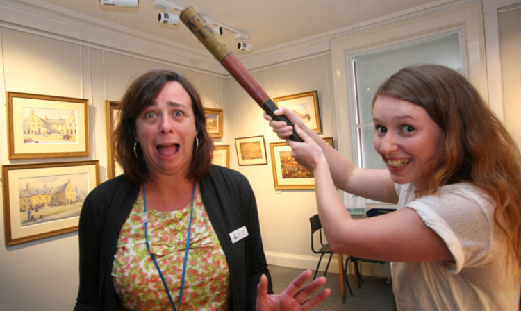 Senior museum assistant Kirsten Couper and assistant Louisa Grossi try out the truncheon.