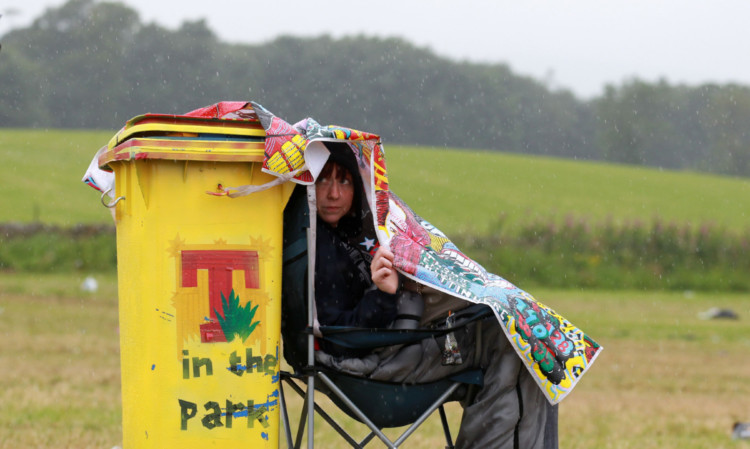 Festival goer Lyndsay Mackie shelters from the rain.