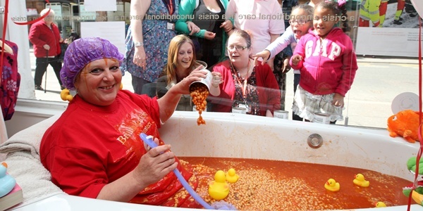 Steve MacDougall, Courier, Red Cross, 19 Kinnoull Street, Perth. Fundraiser sitting in bath of beans in shop window. Pictured, at the front in the tub is Evelyn Birnie, with friends, shop staff and passers-by looking on.