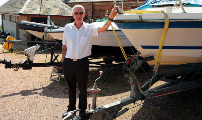 Councillor Tom Adams with some of the abandoned boats blocking the car park and preventing tourists from parking.