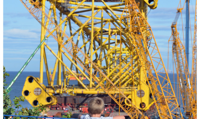 FIve-year-old Cameron Fraser  looks out over BiFab yard at Methil watching the Solan Jacket Making its way on to the barge.