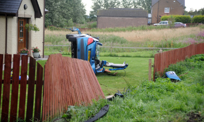 Mr McMartins car on its side after it ploughed through Angela Hills fence.