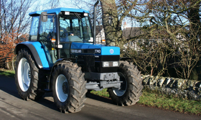 One of the earlier New Holland tractors, this 7740 of Ford origin still has the old Ford name on the front plus the New Holland name and blue leaf logo on the front nose cone.