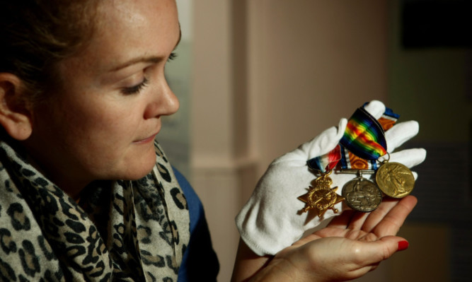 Museum assistant Ruth Nelson with the Mons Star medal, British War Medal and the Allied Victory medal, also known as 'Pip, Squeak and Wilfred'.