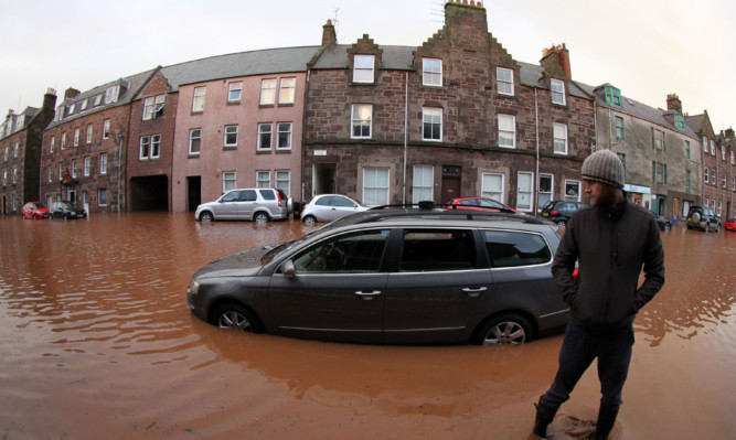 A man views his flooded car on the high street in Stonehaven after heavy flooding two years ago.