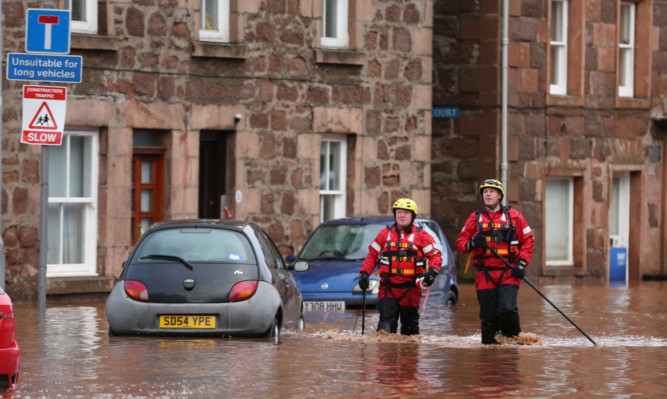 Fireman walk through floodwater on the high street in Stonehave in 2012.