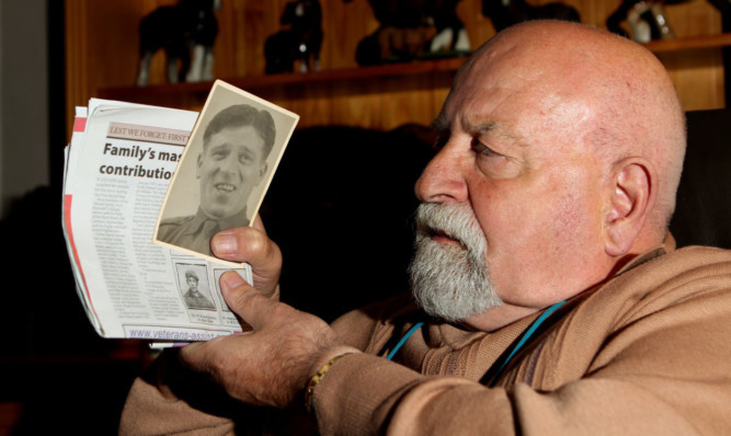 William Stewart holding a photograph of his father David and a copy of The Courier featuring his grandfather David Stewart.