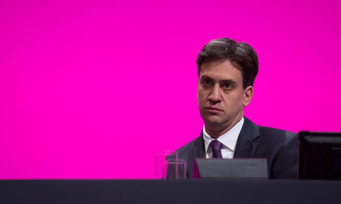 Ed Miliband sits on stage in the main hall of the Labour Party Conference.