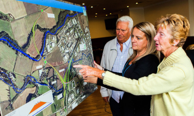Joe and Catherine Wyse examine plans for the new road that will service the school at Bertha Park with Sarah Millar, project manager with Perth and Kinross Council, centre.